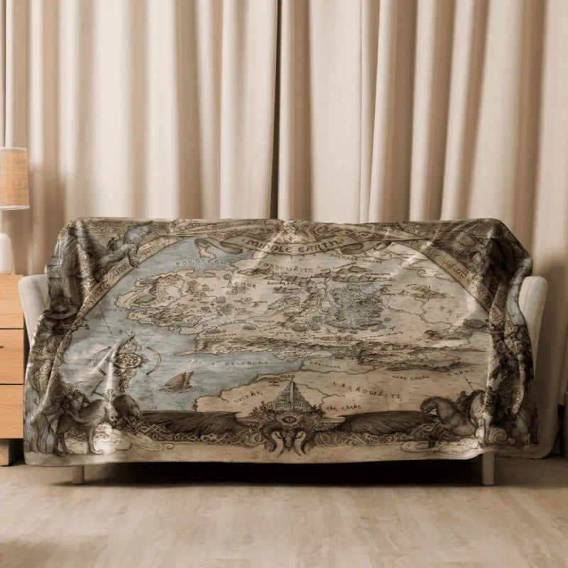 Sofa with a decorative blanket featuring a map design of the Middle Earth in a room with beige curtains.